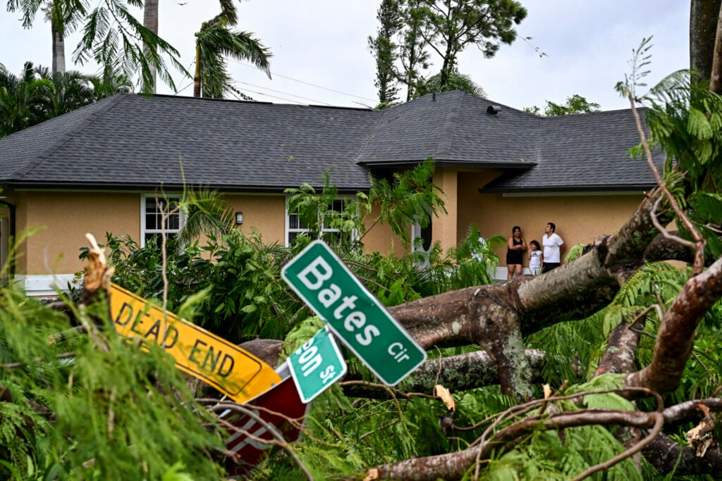 A family stands outside their home after a tornado ripped through Fort Myers, Florida.