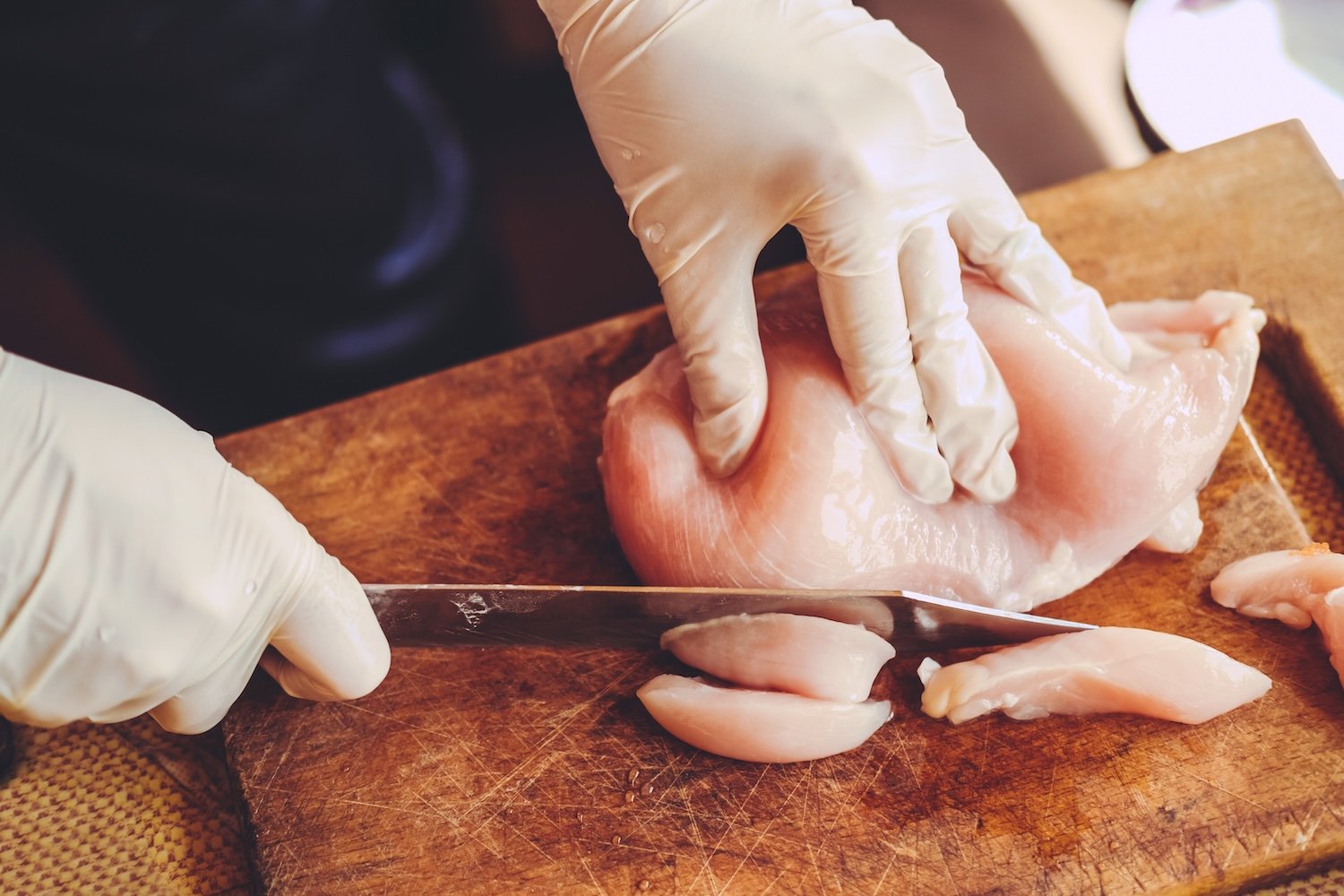 File photo of raw chicken being cut into smaller pieces.